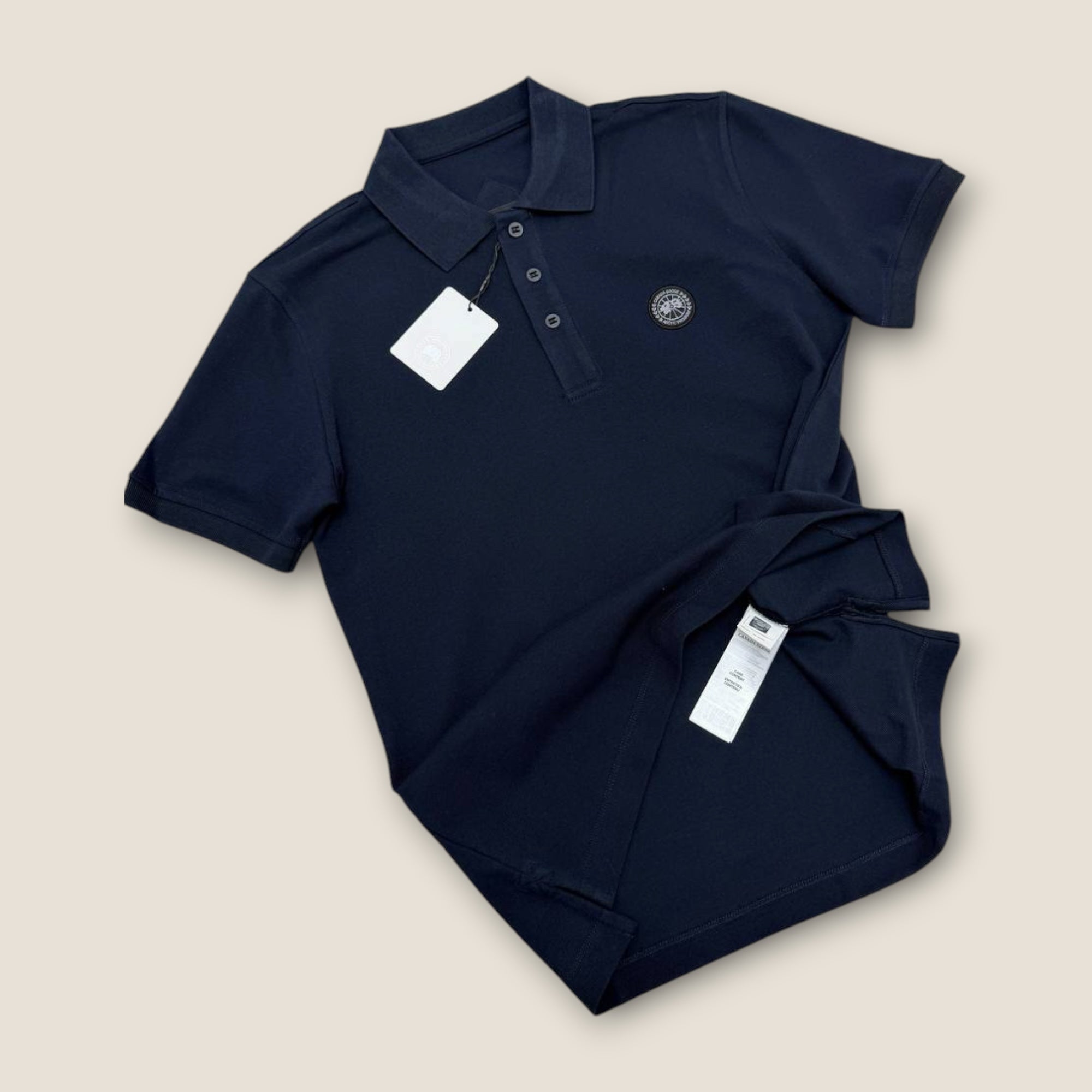 Navy blue polo shirt with a tag on a beige background