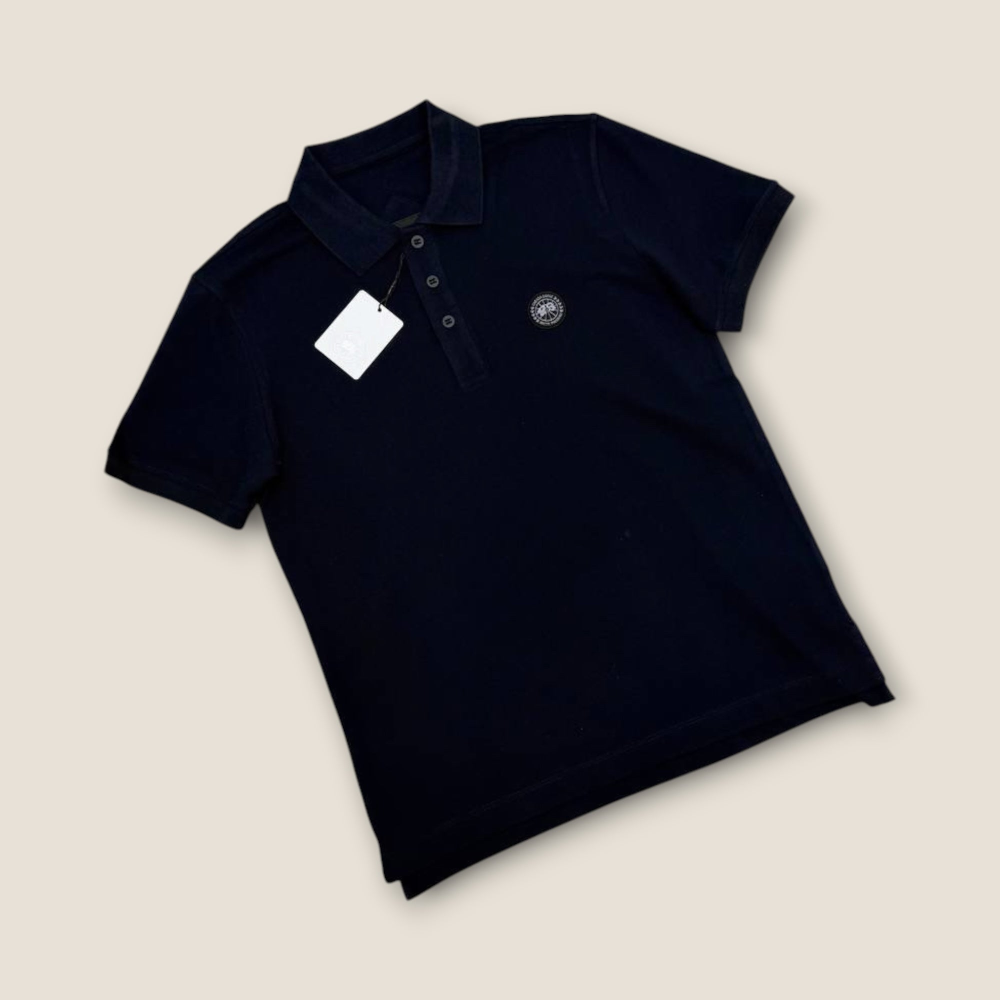 Black polo shirt with a tag on a beige background